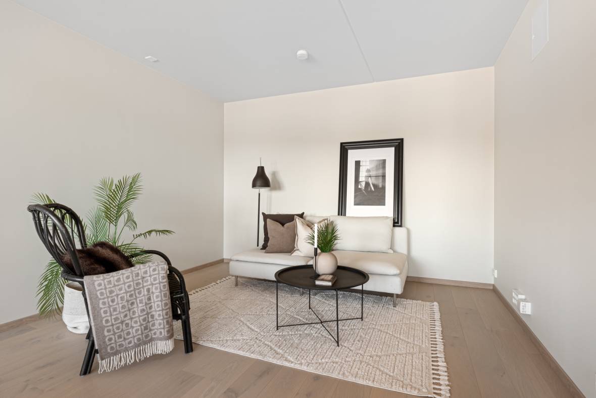 Koselig stue-krok i nybygg med hvit sofa, svart sofabord og planter