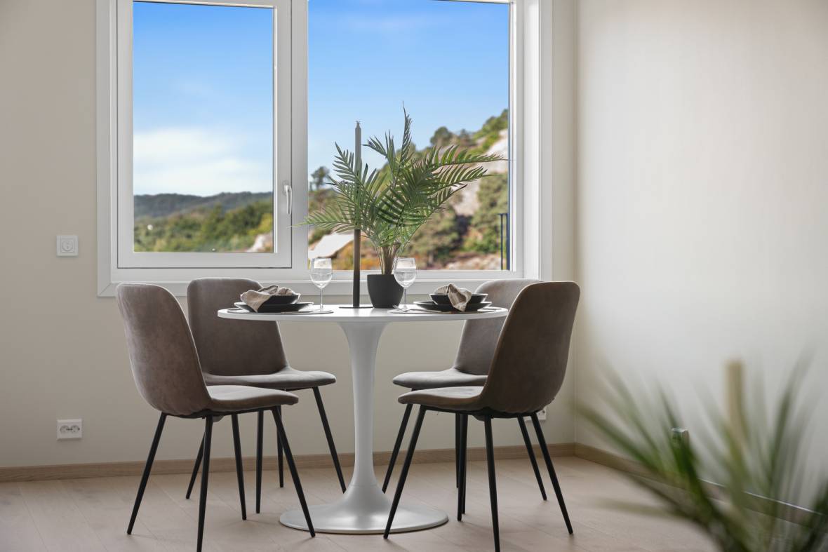 Stylet spiseplass i nybygg med rundt hvitt bord og vinglass